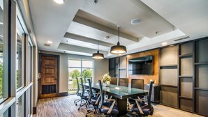 Une salle de conférence moderne, dotée d’une grande table, de chaises et d’un téléviseur fixé au mur.