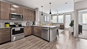 Une cuisine moderne dotée d’appareils électroménagers en acier inoxydable, de meubles en bois et d’un îlot central.