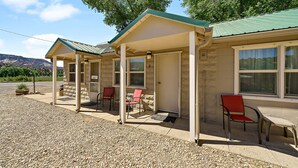 A motel with a covered porch, two red chairs, and a gravel driveway. - Mt Carmel Motel Room close to Zion National Park! (Orderville)
