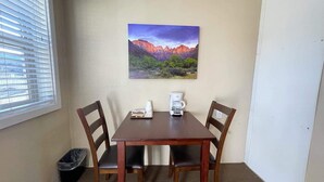 A small dining area with a table, four chairs, a coffee maker, and a painting on the wall. - Mt Carmel Motel Room close to Zion National Park! (Orderville)
