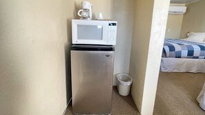 Una kitchenette compacta con microondas, cafetera y un pequeño cubo de basura.