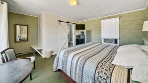 A bedroom with a bed, a chair, a desk, a mirror, and a television. - Mt Carmel Motel close to Zion National Park (Orderville)
