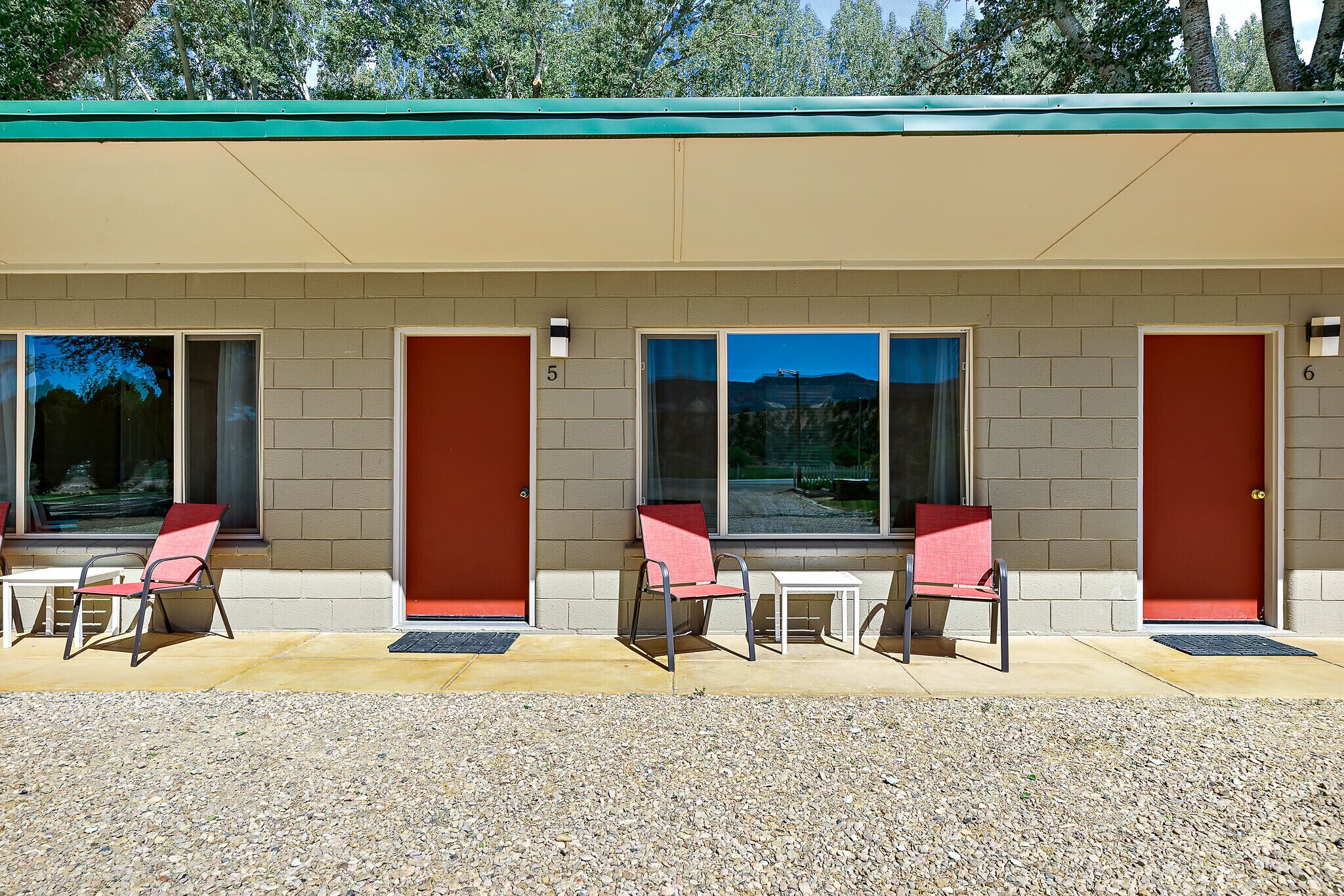 Un motel con habitaciones numeradas, asientos al aire libre y vistas a las montañas.