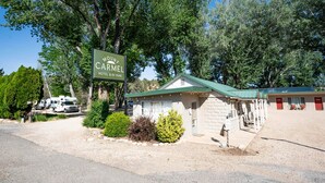 Un motel con un cartel que dice "MOUNT CARMEL MOTEL & RV PARK", que presenta un pequeño edificio de techo verde, un área de estacionamiento y vehículos recreativos.