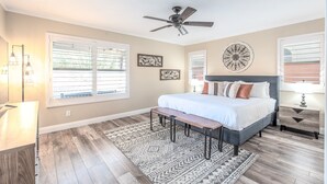 Une chambre à coucher avec un lit, un banc, un ventilateur de plafond et un tapis.