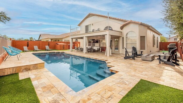 Un jardin avec une piscine, du mobilier de jardin et un espace barbecue.