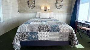 Une chambre à coucher avec un grand lit, deux lampes fixées au mur, un bureau avec une chaise et une fenêtre avec des rideaux.