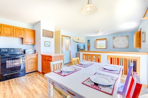 A kitchen with wooden cabinets, a black stove, and a dining area with a table set for four. - Soundside Dog Friendly Home w/ Hot Tub, Smart TVs, and Nearby Beach Access (Avon)