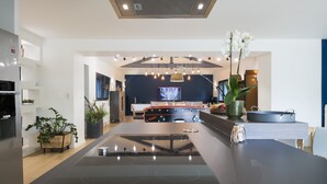 Une cuisine moderne dotée d’un îlot central, d’un four encastré et d’un coin repas avec une table et des chaises.