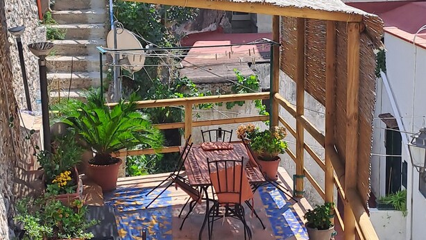 Une terrasse sur le toit, dotée d’un sol carrelé, d’une pergola en bois et de plantes en pot.