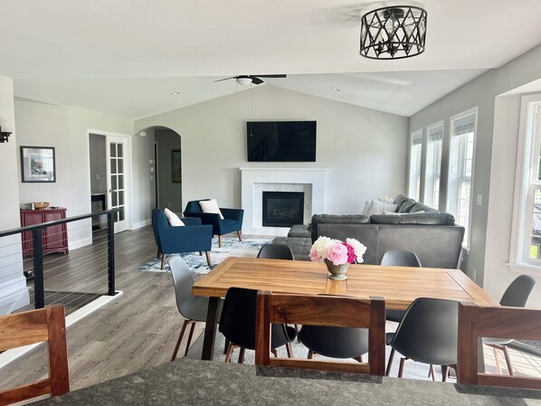 A spacious living room with a fireplace, a dining area with a wooden table, and a modern ceiling fan. - Hidden Gem for Skiing, Fishing, Hiking, Views (Belgrade)