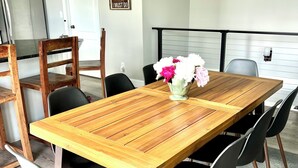 Ein Essbereich mit einem Holztisch, schwarzen Stühlen und einer Blumenvase.