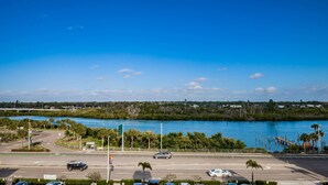 Une route côtière offrant une vue sur l’eau, un parking et un petit bâtiment.
