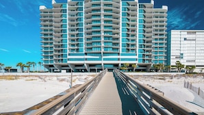 A modern hotel with a curved facade, multiple balconies, and a beach view.