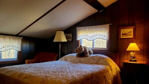 Ein Schlafzimmer mit einem Bett, einem Sessel, einer Lampe und einem Fenster mit Vorhängen.