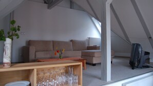 An attic room with a sofa, a wooden table, and a television.