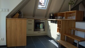 A compact kitchen with a skylight, wooden cabinetry, and a built-in oven.