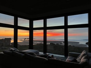 Enjoy a serene beach view from the comfort of this room, featuring a sofa and large window.