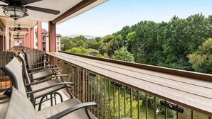 A balcony with outdoor seating and a view of a forested area. - Mountain View Riverfront Condo W/ Balcony, Fishing, Fireplace, Fitness W/ Sauna (Sevierville)