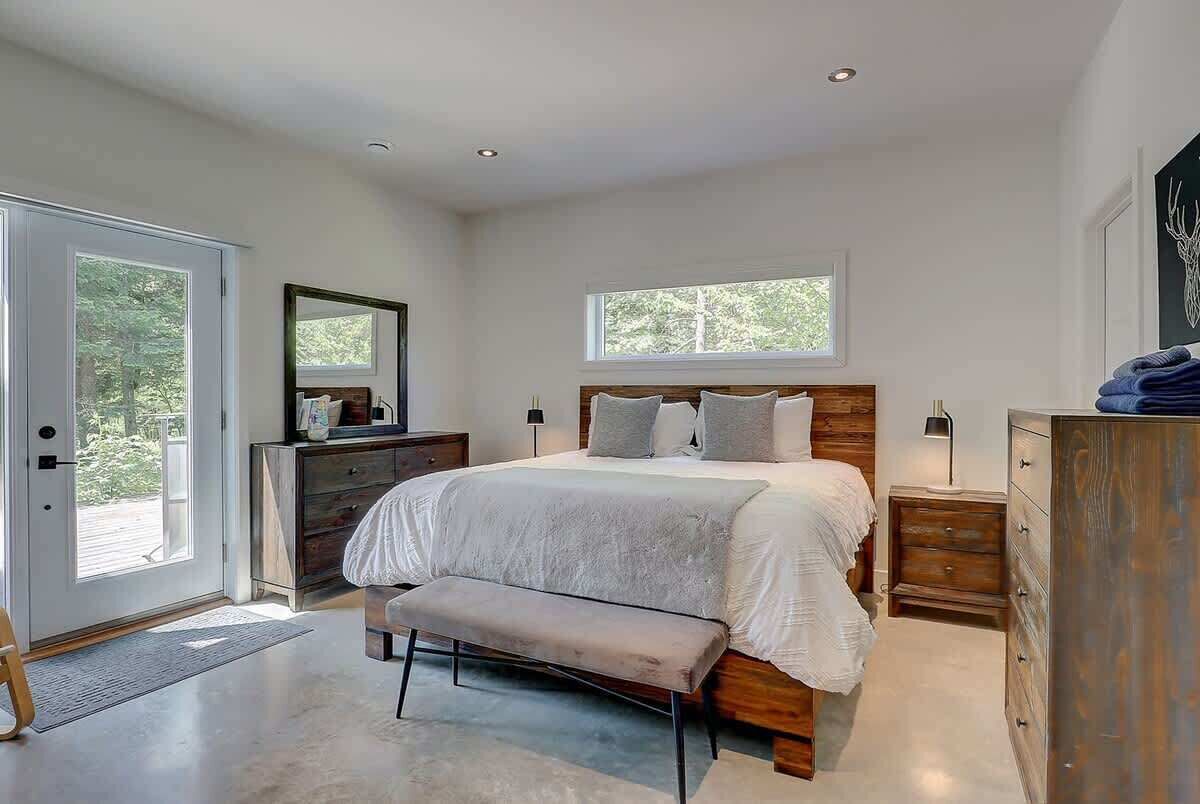 Ein Schlafzimmer mit einem großen Bett, einer Bank, einem Schminktisch und einem Spiegel.