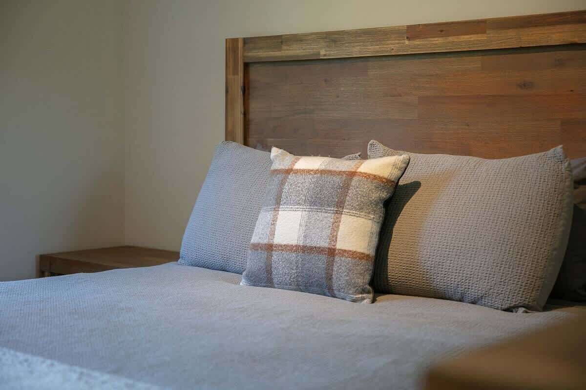 Una cama con cabecera de madera y dos almohadas.
