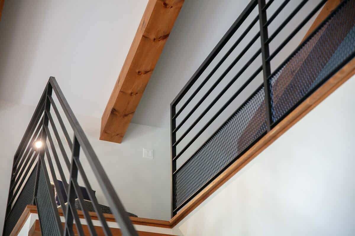 Una moderna scala con trave in legno e ringhiere metalliche.