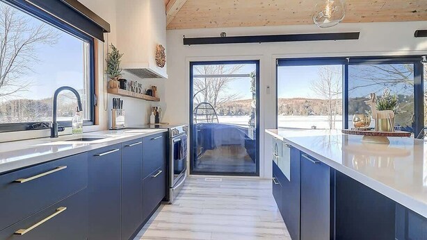 Una cocina moderna con armarios oscuros, un ventanal y vistas al exterior.