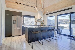 Una cucina moderna con una grande isola, sgabelli da bar e vista panoramica attraverso ampie finestre.