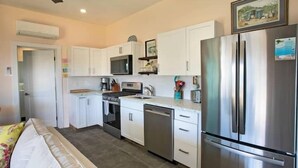 A compact kitchen with white cabinets, a stainless steel refrigerator, a microwave, and a dishwasher.