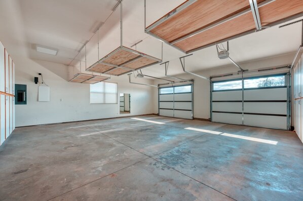 A spacious garage with concrete floors, wooden ceiling beams, and two garage doors.
