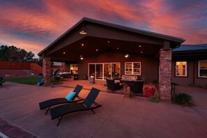 A covered patio with outdoor furniture, a hot tub, and a fire pit.