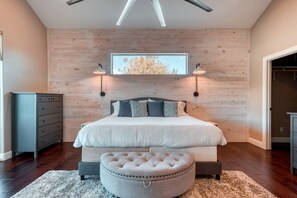 A bedroom with a large bed, two wall-mounted lights, a window with a view, and a wooden wall.