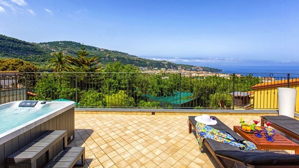 A rooftop terrace with a hot tub, lounge chairs, and a scenic view of the sea and hills. - Eterea Charming Suites (Sorrento)