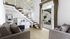 A modern living room with a staircase, a sofa, and a dining area. - Eterea Charming Suites (Sorrento)