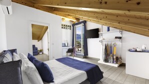A bedroom with a bed, a TV, and a balcony with umbrellas. - Eterea Charming Suites (Sorrento)