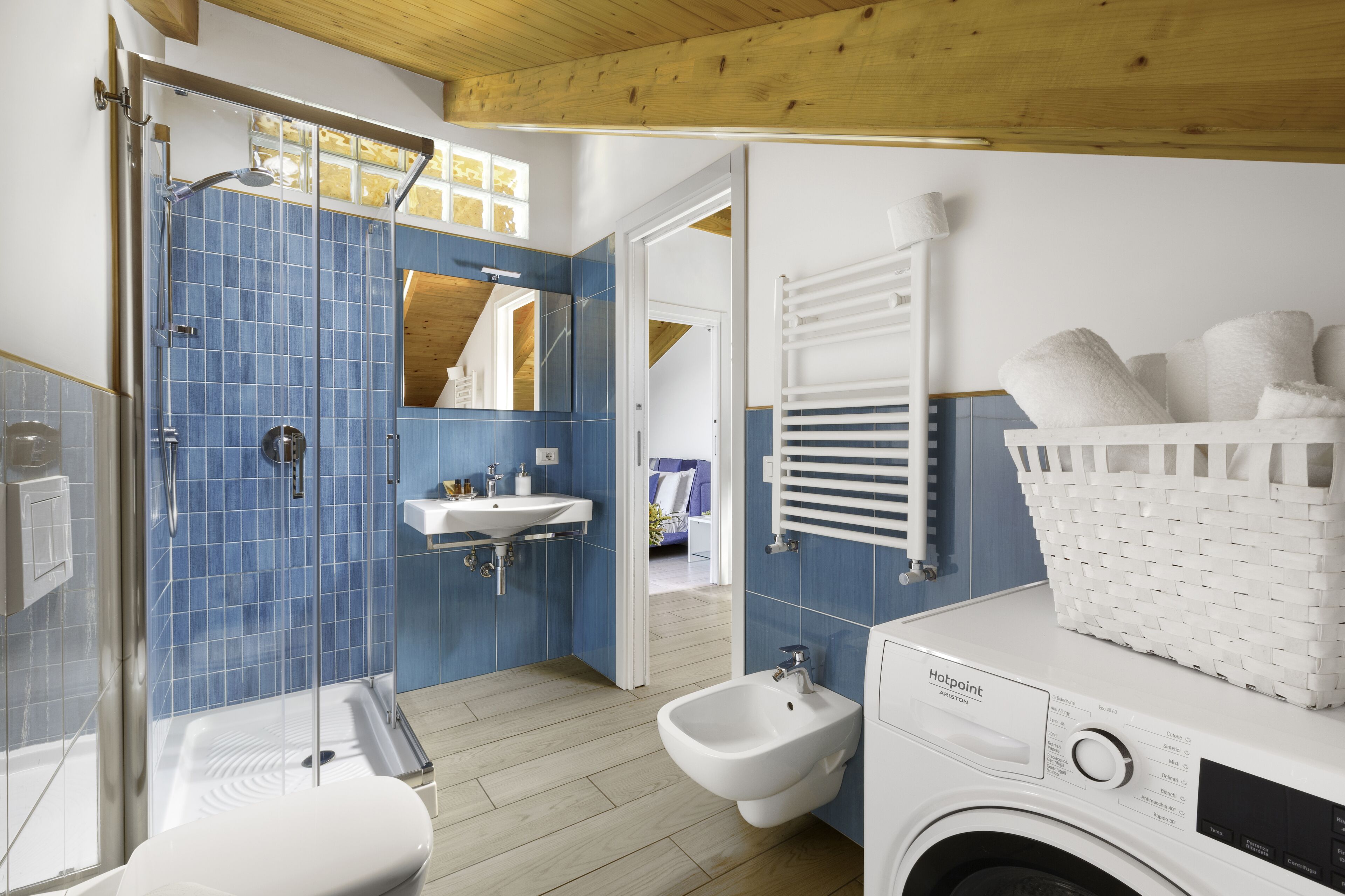 A modern bathroom with a shower, bidet, sink, and a washing machine.
