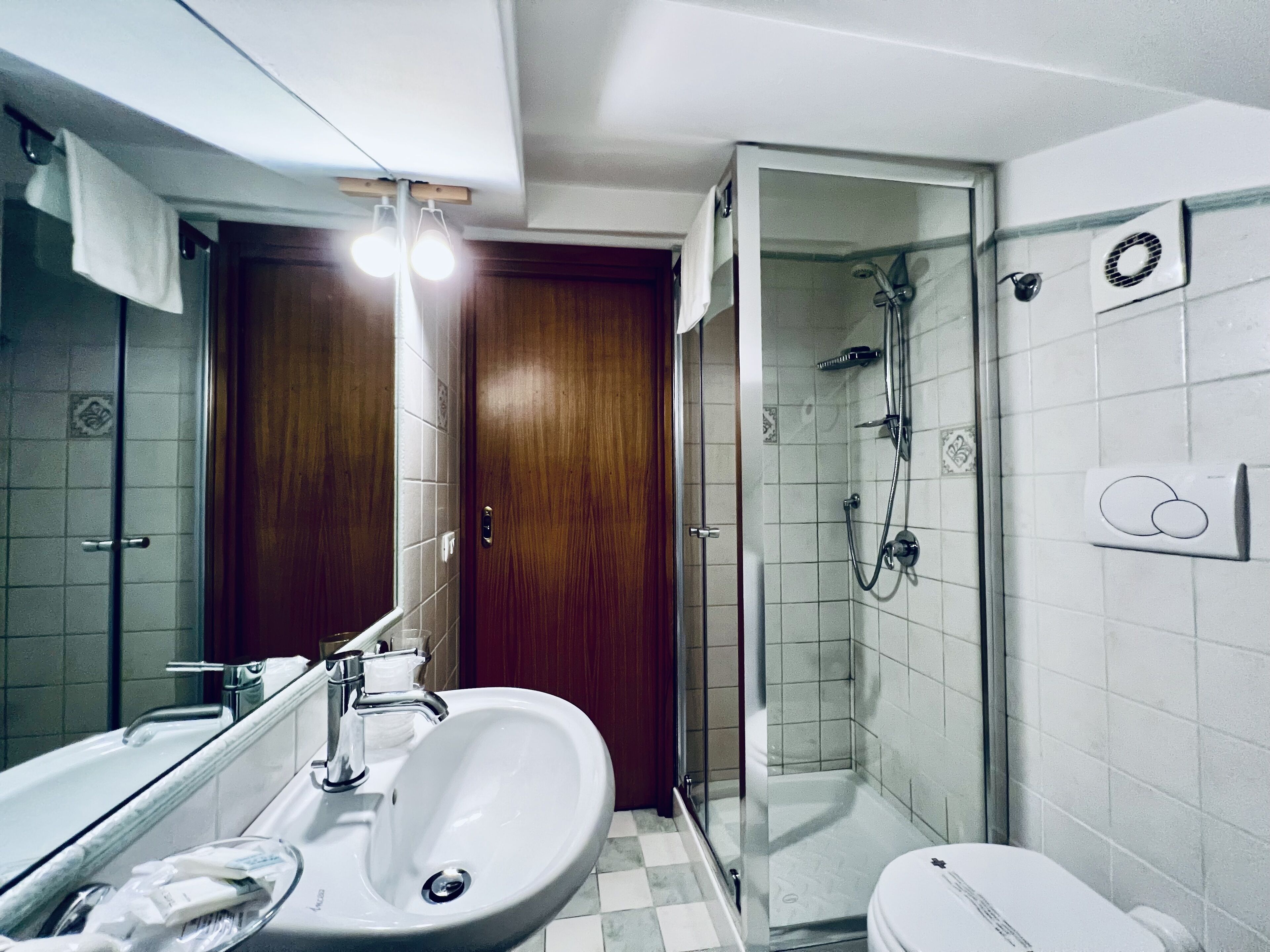 A bathroom with a sink, mirror, toilet, and shower.