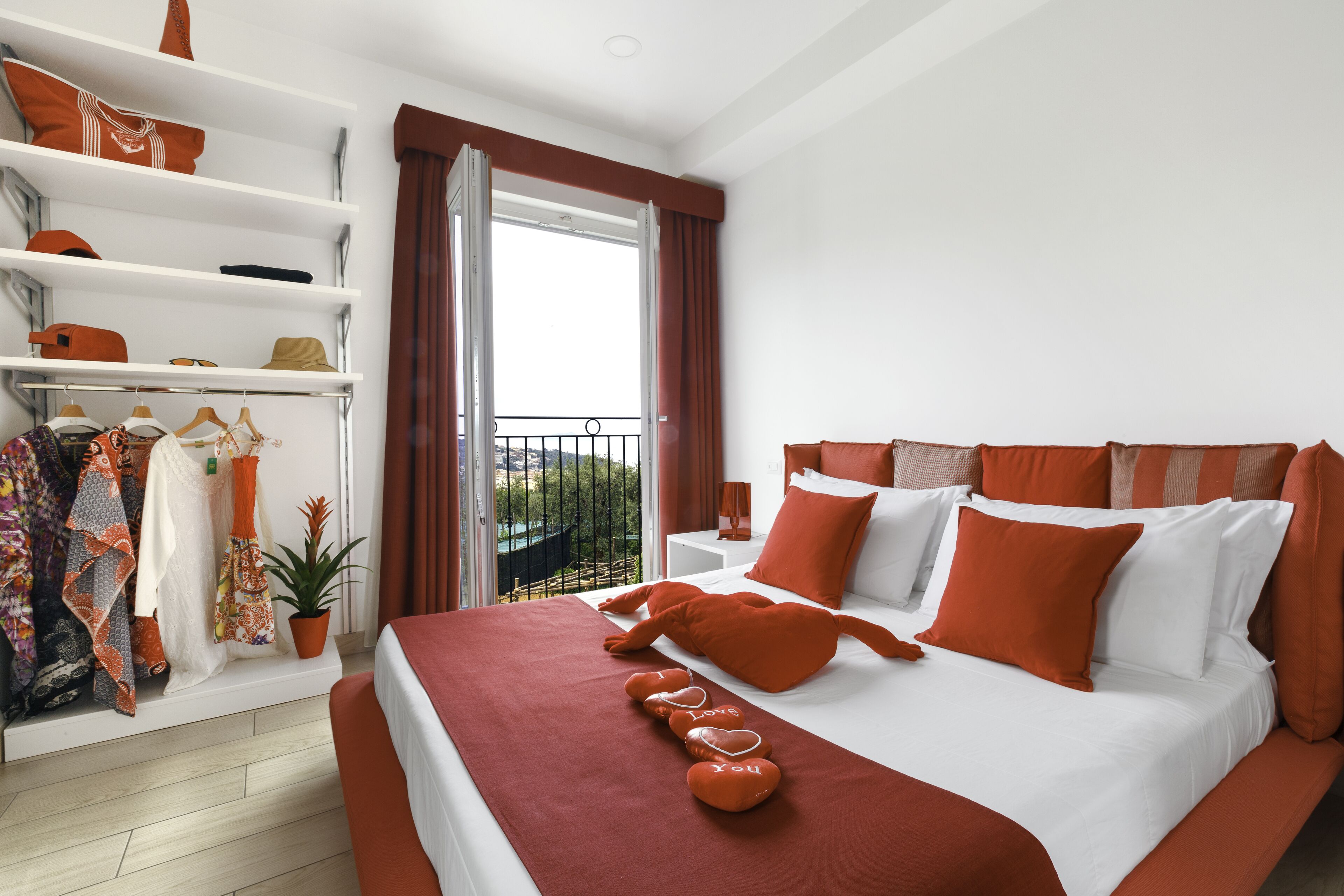 Una habitación de hotel moderna con una cama grande, un armario, un balcón y una planta en maceta.