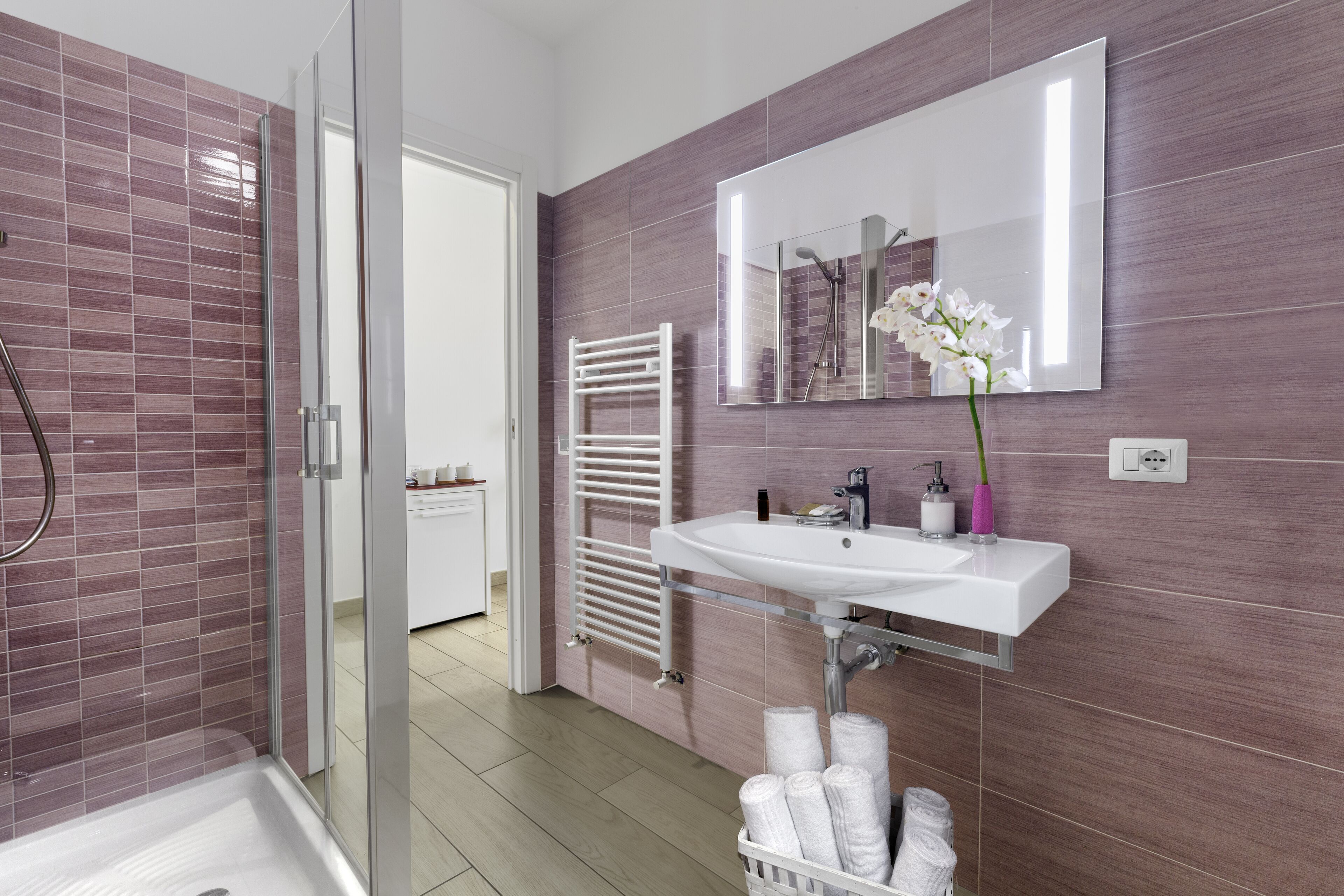 Un bagno moderno con box doccia in vetro, lavandino bianco e porta asciugamani.