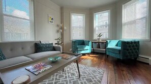 Un salon avec un canapé, deux fauteuils, une table basse et un tapis.