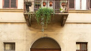 A building with a large wooden door, a balcony with plants, and a no parking sign. - Santa chiara suite 2, studio in historic center  (Torino)