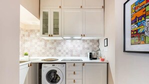 A compact kitchen with a washing machine, a coffee maker, and a small countertop. - Santa chiara suite 2, studio in historic center  (Torino)
