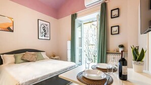 A hotel room with a bed, a dining table set with plates, a bottle of wine, and a potted plant. - Santa chiara suite 2, studio in historic center  (Torino)