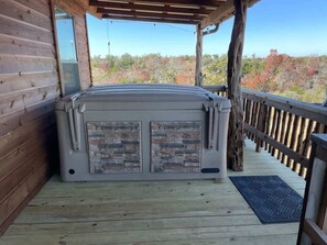 A hot tub on a wooden deck with a view of trees.