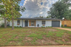 A single-story house with a front porch, a garage, and a well-maintained lawn. - Stylish Abode | Minutes to Main St! (Fredericksburg)