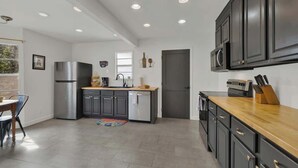 Una cocina moderna con armarios oscuros, electrodomésticos de acero inoxidable y encimera de madera.