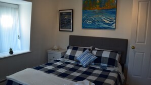 A neatly made bed with a checkered bedspread, a pillow, and a folded towel on the floor. - Quebec Château Richer Côte de Beaupré Canada rent a 4 ½ furnished plus more.... (Chateau-Richer)