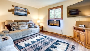 A living room with a beige sofa, a patterned rug, a fireplace, and a television.