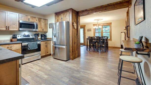 A kitchen with wooden cabinets, stainless steel appliances, and a dining area with a table and chairs.