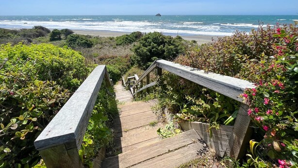 A wooden staircase leading to a beach with ocean views.